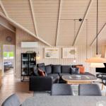 Wohnzimmer mit Sofa, Tisch und Stühlen. Holzwände und Decke. Blick in Schlafzimmer.