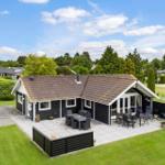 Schwarzes Ferienhaus mit Terrasse und Garten. Holzterrasse mit Sitzgelegenheiten.