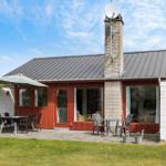 Ein Haus mit rotem Holz, grauem Dach und Terrasse mit Tisch und Stühlen.