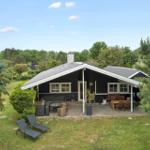 Schwarze Hütte mit Terrasse, Garten und Außensitzgelegenheiten.