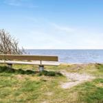 Holzbank am Strand mit Blick auf das Meer und einen bewachsenen Hang.