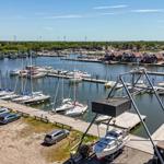 Hafen mit Booten, Steg und Häusern am Wasser.