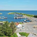 Hafen mit Booten, kleinem Parkplatz und Blick auf das Meer.