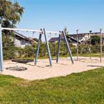Spielplatz mit Schaukel und Klettergerüst auf Sandfläche