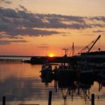 Sonnenuntergang über Hafen mit Booten und Kränen