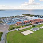 Hafen mit Booten, roten Häusern und Sportanlagen am Wasser.