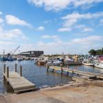 Hafen mit Booten und Stegen unter blauem Himmel.