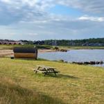 Holzbank und Sauna am Wasser, Blick auf Ferienhäuser im Hintergrund.