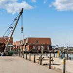 Hafen mit Krane, roten Häusern und Booten im Hintergrund.