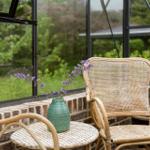 Rattan-Stuhl und Tisch mit Vasenblumen vor Glaswand