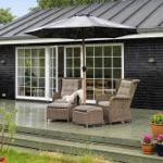 Terrasse mit Sitzgelegenheit unter Sonnenschirm, Pflanzen und Blick ins Haus.