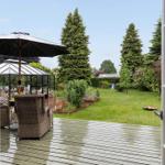 Terrasse mit Sitzgelegenheiten und Garten mit Bäumen und Beeten.
