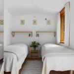 Zwei Betten mit weißen Bettdecken, Holzrahmenfenster und Wandbilder.