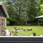 Hinter dem Haus befindet sich ein großer Garten mit Tisch, Bänken und Sonnenschirm.