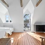 Zwei Betten, Holzfußboden, Dachschrägen und Fenster mit Blick auf Balkon.