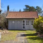 Ein kleines Haus mit rotem Ziegeldach und weißer Tür im Garten.