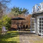 Haus mit Terrasse, Garten, Sitzgelegenheiten und Sonnenschutz.