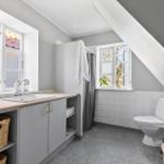 Badezimmer mit Waschbecken, Toilette und Dusche unter Dachschräge.