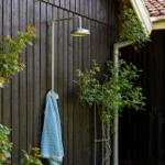 Außendusche an Holzwand mit Handtuch und Pflanzen
