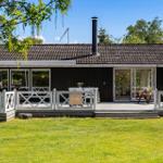 Ein Haus mit Terrasse, Garten und Schornstein. Durchgehende Glasfronten.