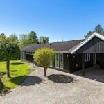 Schwarzes Holzhaus mit Steinweg und Garten. Nummer 18. Klare Sicht auf das Gebäude.