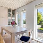 Esszimmer mit Holztisch, weißen Stühlen und Blick auf Garten.