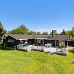 Ein Haus mit Terrasse, Grill und Garten unter blauem Himmel.