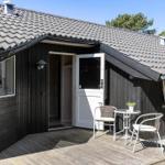 Haus mit Holzveranda, weiße Tür und Tisch mit zwei Stühlen.