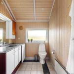 Badezimmer mit Holzwand, Waschbecken, Toilette und Fenster.