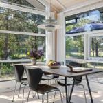 Essbereich mit Tisch und Stühlen. Große Fenster bieten Blick auf Wald und Terrasse.