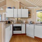 Küche mit weißen Schränken, Holzdecke und Fenster zum Garten