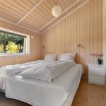 Schlafzimmer mit Bett, Fenster und Holzwandverkleidung. Neben dem Bett steht ein Nachttisch.