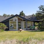 Moderne Villa mit großem Garten und Terrasse. Grüne Sitzgelegenheiten und Bäume umgeben das Haus.