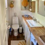 Badezimmer mit Waschmaschine, Waschtisch und Toilette. Holzoberfläche und Spiegel sichtbar.