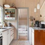 Küche mit Arbeitsplatte, Spüle und Fenster. Durchgang zu Schlafzimmer mit Bett.