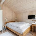 Schlafzimmer mit Holzwand, Bett, Schreibtisch und Fernseher