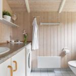 Badezimmer mit Holzwand, Waschbecken, Toilette und Badewanne.