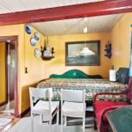 Schlafzimmer mit Bett, Tisch und Stühlen. Wand mit Bild und dekorativen Tellern.