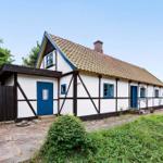 Ein weißes Fachwerkhaus mit blauen Fenstern und Tür unter einem Ziegeldach.