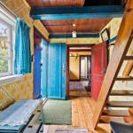 Haus mit Holztreppe, blauer Tür und gelbem Tapetenmuster an den Wänden.