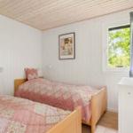 Zwei Betten mit rosa Quilt, Fernseher und Fenster mit Blick auf Grün.