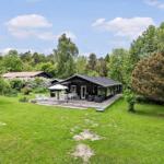 Schwarze Hütte mit Terrasse, Garten und Grillplatz im Grünen.
