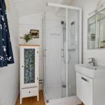 Dusche, Waschbecken und Kleiderschrank in einem hellen Badezimmer mit Holzboden und blauem Vorhang.