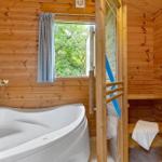 Bad mit Whirlpool und angrenzender Sauna mit Holzwand und Fenster.