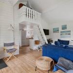 Wohnzimmer mit Kamin, blauem Sofa und Treppe zur Galerie.