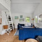 Wohnzimmer mit blauem Sofa, Holzboden und Treppe zur oberen Etage.