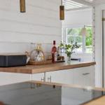 Küche mit Holzoberfläche, weißen Schränken und Fensterblick