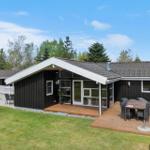 Moderne Holzhütte mit Terrasse, Garten und Grillbereich. Gepflegte Umgebung mit Bäumen.
