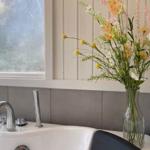 Waschbecken mit Blumenarrangement und Fenster im Badezimmer
