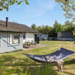 Garten mit Tisch, Stuhl und Hühnern. Vogelhaus und Sträucher im Hintergrund.